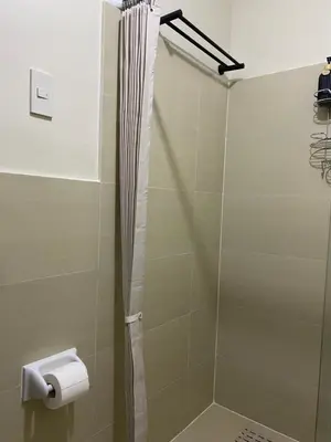 a bathroom with a shower with a toilet paper dispenser at The Stayhaus by Dan & Steph in Manila