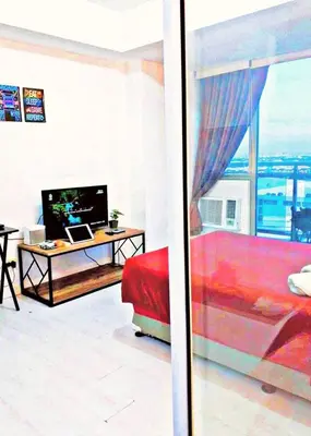 a living room with a red couch and a desk with a computer at Azure Paris Hilton Resort and hotel 1 bedroom for 4pax in Manila