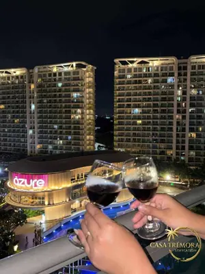 two people holding glasses of wine on a balcony at Azure Paris Hilton Resort and hotel 1 bedroom for 4pax in Manila