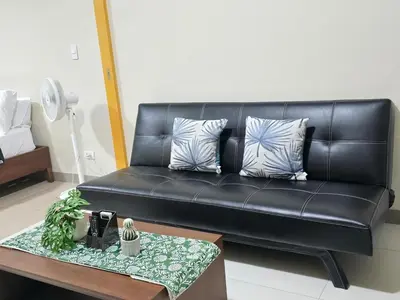 a black leather couch in a living room with a table at Modern BGC One Uptown 1BR near Grand Hyatt Uptown Mitsukoshi Malls and St Lukes Medical Center in Manila