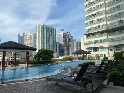 a swimming pool with chairs and umbrellas in a city at Cozy Condo at MakatiCBD in Manila