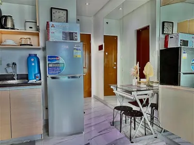 a kitchen with a refrigerator and a table with chairs at Cozy Condo at MakatiCBD in Manila