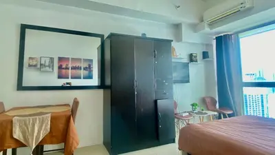 a bedroom with a table and a cabinet and a bed at High End Penthouse Makati CBD in Manila