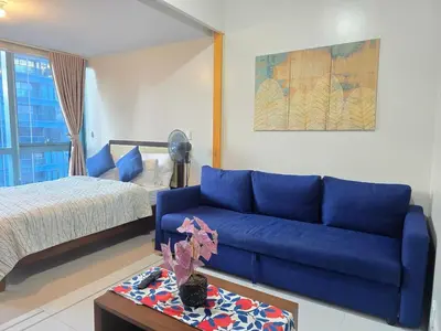 a living room with a blue couch and a bed at Beautiful Sunset One Uptown near Grand Hyatt BGC Uptown, St Lukes Medical Center, and Mitsukoshi Mall in Manila