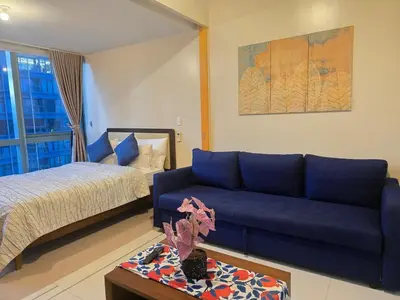 a living room with a blue couch and a bed at Beautiful Sunset One Uptown near Grand Hyatt BGC Uptown, St Lukes Medical Center, and Mitsukoshi Mall in Manila