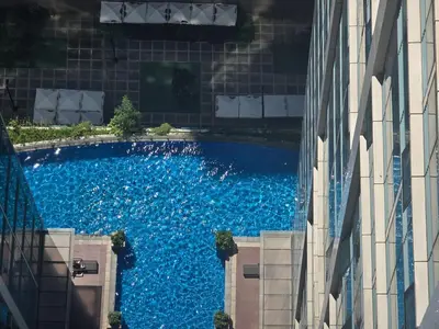 an overhead view of a blue swimming pool between two buildings at Beautiful Sunset One Uptown near Grand Hyatt BGC Uptown, St Lukes Medical Center, and Mitsukoshi Mall in Manila