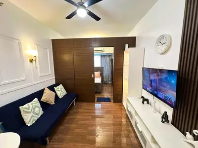 a living room with a blue couch and a flat screen tv at City Comfort Staycation 1BR Air Residences Makati in Manila