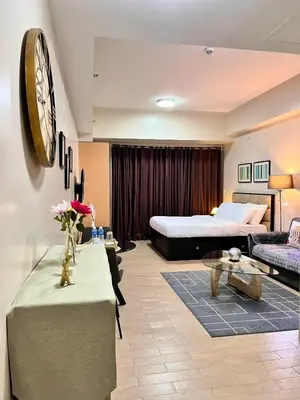 a hotel room with a bed and a living room at Big Studio Unit in Newport near NAIA w Balcony in Manila