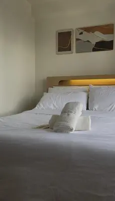 a white bed with two pillows on it at The Camden Place in Manila