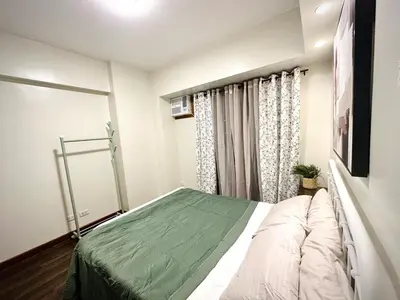 a bedroom with a bed with a green blanket at NEW 2-Bedroom 2-Bath Condo - Flair Towers, near Greenfield District, Ortigas in Manila