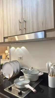 a kitchen with three pans on a stove top at CozyCalmStaycation in Manila