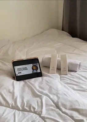 a tablet sitting on top of a bed with towels at CozyCalmStaycation in Manila