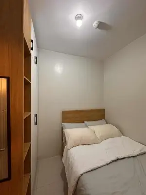 a small bedroom with a bed with white sheets at EuEL Condo in Manila