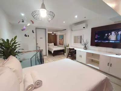 a bedroom with a white bed and a flat screen tv at L1 Twin Bed Staycation in BGC in Manila