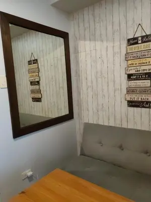 a mirror on a wall with a bench in a room at Apartment Shell Residences near MOA in Manila