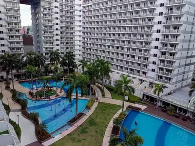 an aerial view of a large swimming pool with tall buildings at Apartment Shell Residences near MOA in Manila