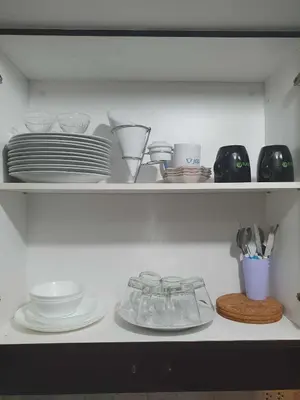 a shelf filled with plates and bowls and dishes at Doc Odette Studio Staycation in Manila