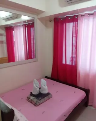 a room with pink curtains and white shoes on a bed at 10th Floor Staycation in Manila