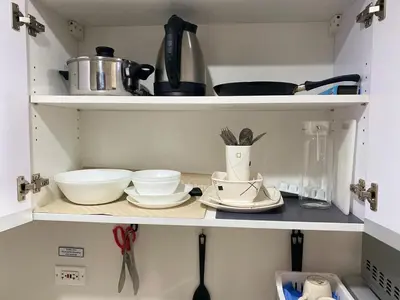 a shelf with bowls and utensils in a kitchen at Sunrise Haven in Makati AIR Residences in Manila