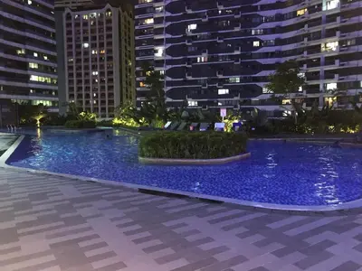 a large swimming pool at night with tall buildings at Affordable Condo in Makati Air Residences in Manila