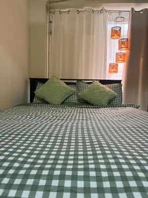 a bed with green and white checkered sheets and pillows at Casita avec Amour at Lumiere Residences in Manila