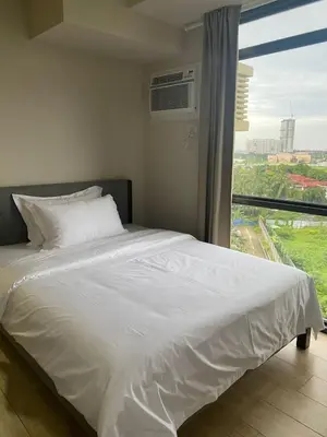 a bedroom with a white bed with a large window at Gentry Manor 1BR with Balcony Near Okada - 6A in Manila