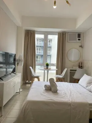 a bedroom with a white bed and a table and chairs at Kasara Pasig Staycation in Manila