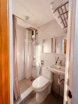 a white bathroom with a toilet and a sink at G's Bnb in Manila