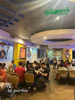 a group of people sitting at tables in a restaurant at 2 Bedroom Unit with Queen-sized Beds near NAIA T3 in Manila