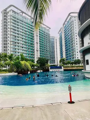 a group of people in a swimming pool with tall buildings at Azure Luxe Suites in Azure Bicutan Near NAIA and MOA in Manila