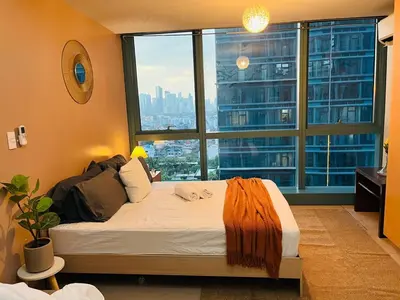 a bedroom with a large bed with a large window at Bgc One Uptown Residences in Manila