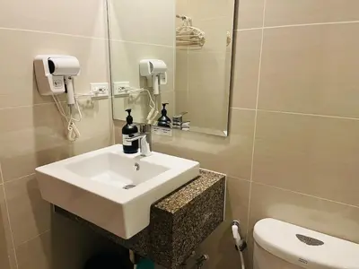 a bathroom with a sink and a toilet and a mirror at Bgc One Uptown Residences in Manila