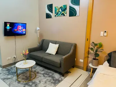 a living room with a couch and a tv at Bgc One Uptown Residences in Manila