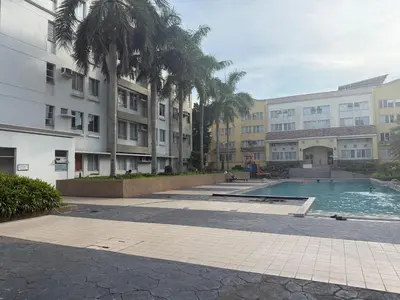 a swimming pool in a courtyard with palm trees and buildings at Cypress 108 in Manggahan