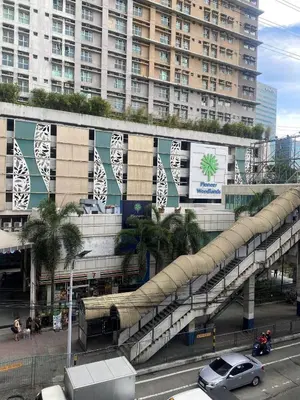 a building with an escalator in front of a city at Cozy 1BR Pioneer Woodland SM Light Boni Mandaluyong in Manila