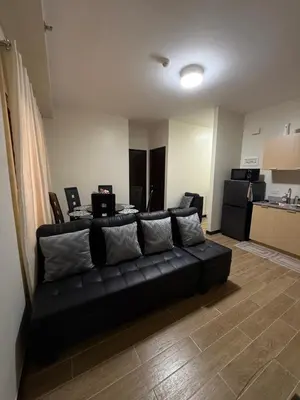 a black couch in a living room with a kitchen at Paseo Verde at Real in Manila