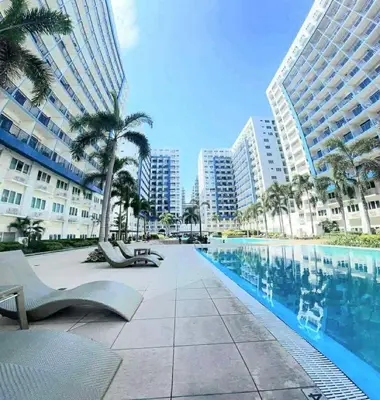 a swimming pool with palm trees and buildings at 1Br Sea Residences affordable staycatiom in Manila
