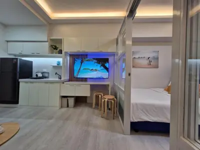 a small bedroom with a bed and a kitchen at Grace Residences Taguig in Manila