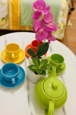 a table with plates and a vase with flowers on it at La Verti Residences 1520 in Manila