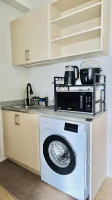 a kitchen with a microwave and a washing machine at The Hive Cozy 1-BR Retreat in Taytay