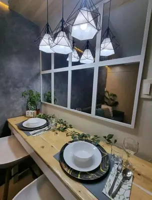 a dining room table with plates and glasses and lights at cozy room at Sea Res in Manila