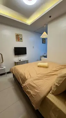a bedroom with a large bed and a tv at TGG Suites at Birch Tower in Manila