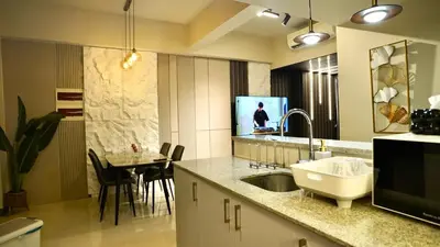 a kitchen with a sink and a tv and a table at Luxury 2BR in Uptown Parksuites BGC Balcony & Prime location in Manila