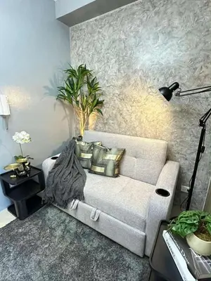 a living room with a white couch with pillows at Sakura Suite at Shore 2 in Manila