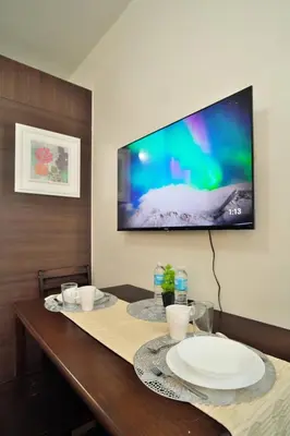 a dining room table with a television on the wall at The Dream Scape SMDC Air Residences Makati in Manila