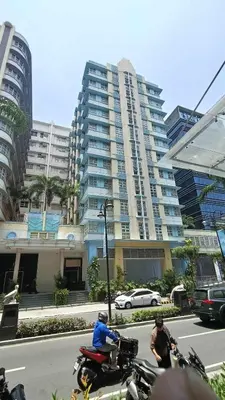 two people riding motorcycles on a city street with a tall building at Manila Airport Hub near NAIA T3 -101 Newport Boulevard in Manila