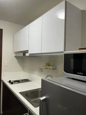 a kitchen with white cabinets and a sink and a microwave at The Urban Crib SMDC Residences Makati in Manila