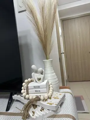 a table topped with a vase with a stack of books at Pyeong on Suite SMDC Shore Residences Mall of Asia Pasay in Manila