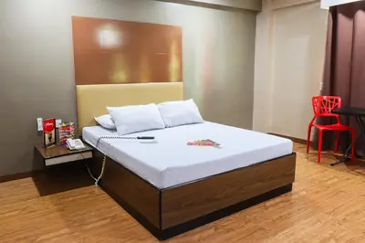 a bed in a room with a red chair at Hotel Sogo Baclaran in Manila