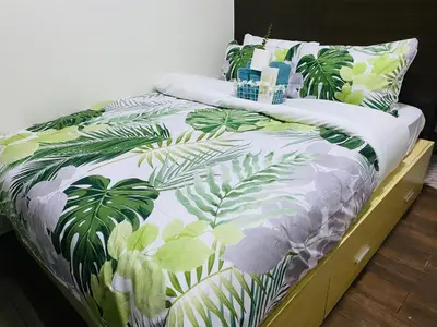 a bed with a green and white bedspread with palm leaves at City View Skyline - Air Residence in Manila
